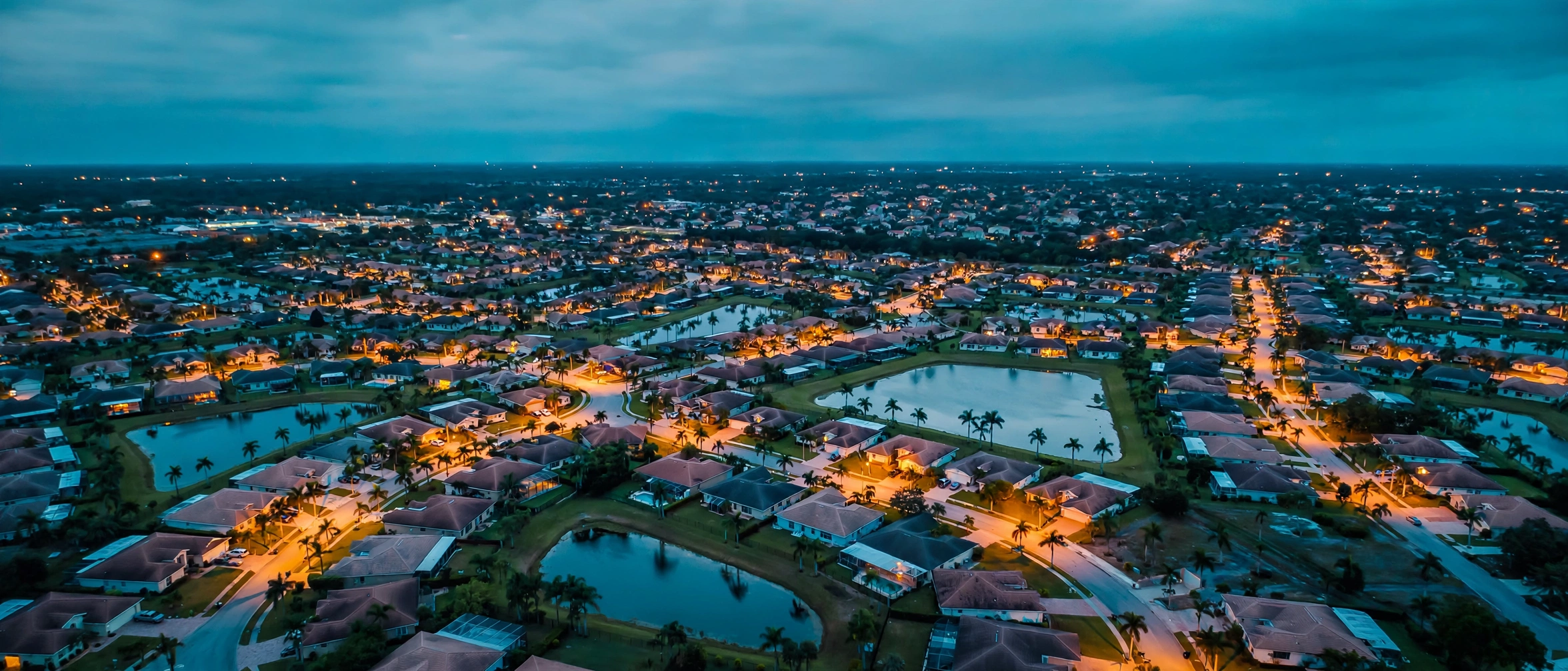 Aerial view of a Florida subdivision at dusk, streets and ponds lit house by house